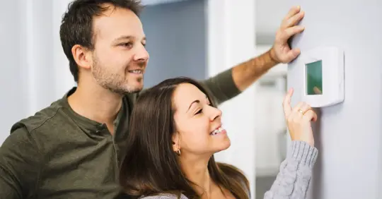Couple adjusting thermostat