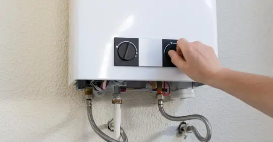 hand adjusting the temperature dial on a tankless gas water heater