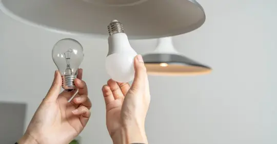 Person replacing fluorescent light bulbs (CFL) with new LED bulbs